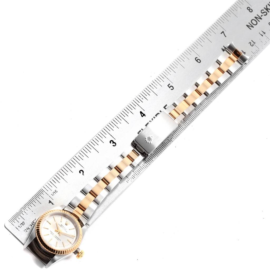 The image shows a Rolex Oyster Perpetual 76193 Women's Steel and Gold (two tone) Silver Dial 76193 Women's Steel and Gold (two tone) Silver Dial watch laid next to a ruler, displaying the watch face and bracelet.