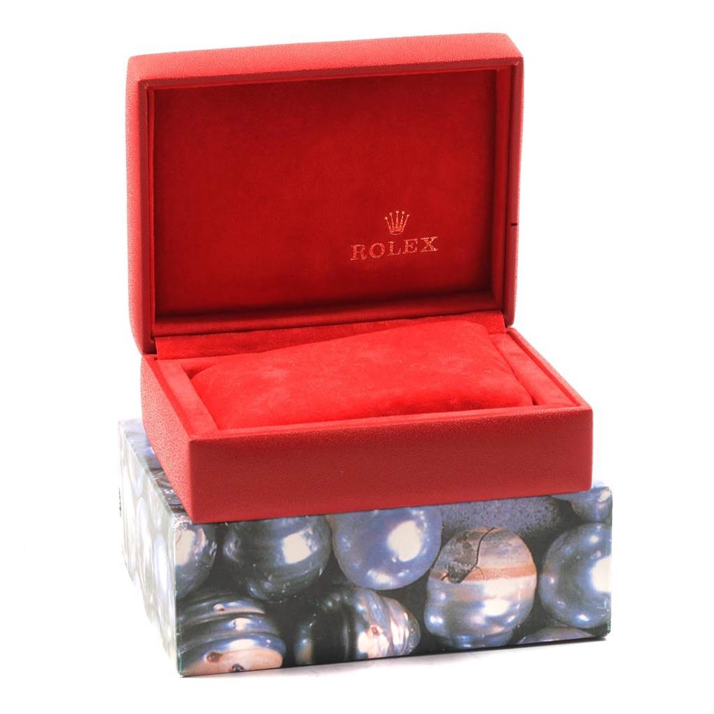 The image shows a red Rolex box for the Oyster Perpetual model, with its lid open and resting on an ornamental outer box.