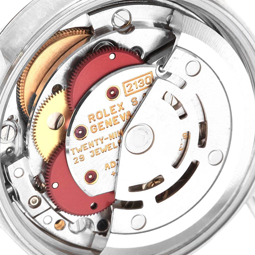 The image shows the movement mechanism of a Rolex Oyster Perpetual 67180 Women's Stainless Steel White Dial 67180 Women's Stainless Steel White Dial watch, highlighting the intricate gears and components.