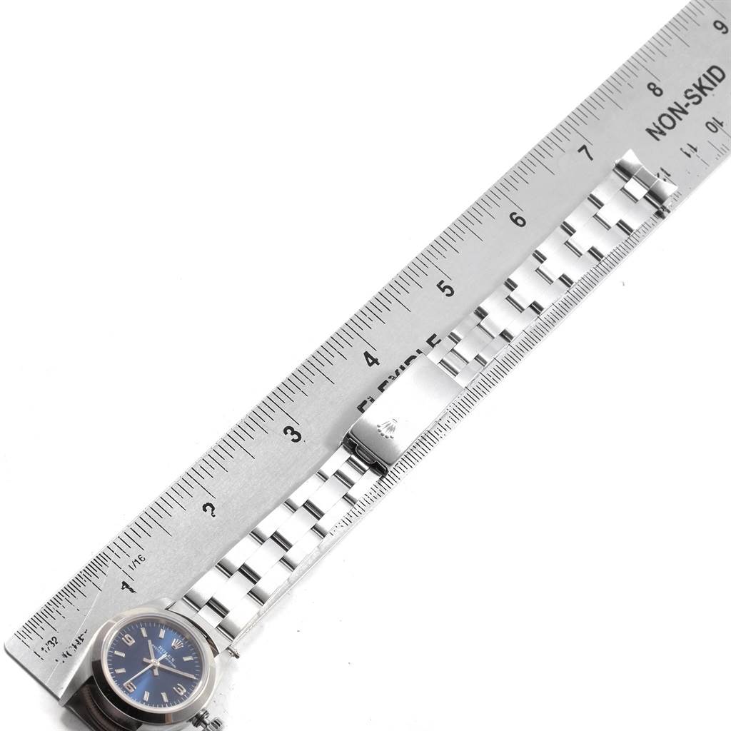 This image shows a flat-lay view of a Rolex Oyster Perpetual 67180 Women's Stainless Steel Blue Dial 67180 Women's Stainless Steel Blue Dial watch and stainless-steel bracelet measured against a ruler.