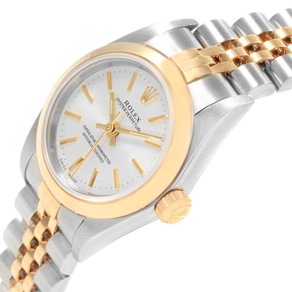 This Rolex Oyster Perpetual 76183 Women's Steel and Gold (two tone) Silver Dial 76183 Women's Steel and Gold (two tone) Silver Dial watch is shown from an oblique angle, displaying the dial, crown, case, and part of the bracelet.