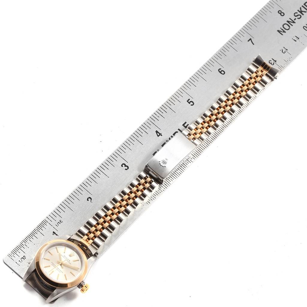The image shows a top view of a Rolex Oyster Perpetual 76183 Women's Steel and Gold (two tone) Silver Dial 76183 Women's Steel and Gold (two tone) Silver Dial watch alongside a ruler, displaying the face and two-tone metal bracelet.