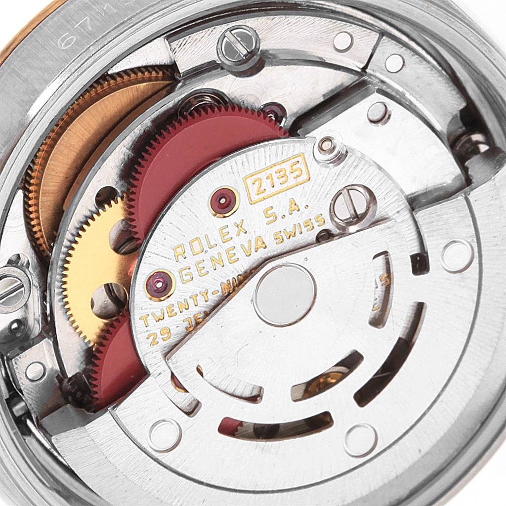 The image shows a close-up of the internal mechanism of a Rolex Oyster Perpetual 67193 Women
s Steel and Gold (two tone) Champagne Dial 67193 Women
s Steel and Gold (two tone) Champagne Dial watch, focusing on gears and the rotor.