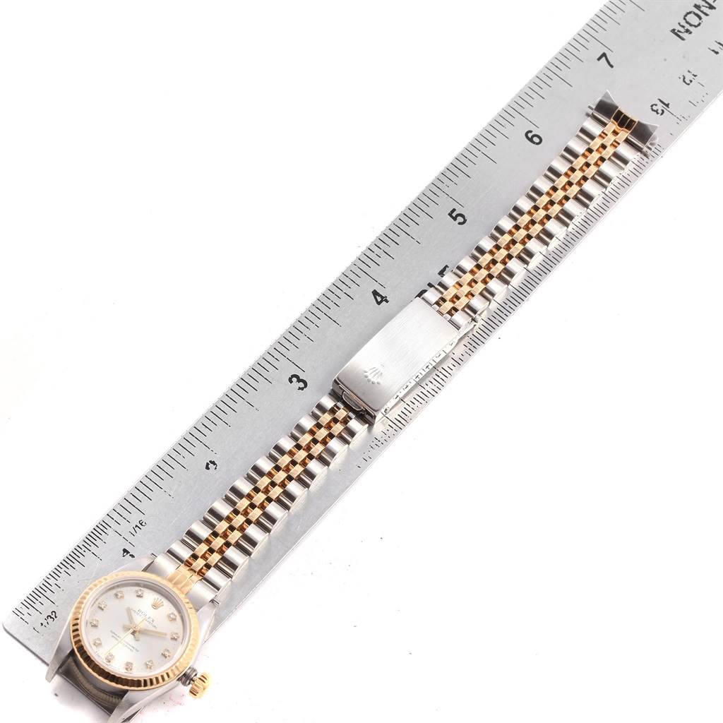 The image shows the full length of a Rolex Oyster Perpetual 67193 Women
s Steel and Gold (two tone) Silver Dial 67193 Women
s Steel and Gold (two tone) Silver Dial watch, including the face and band, measured against a ruler.