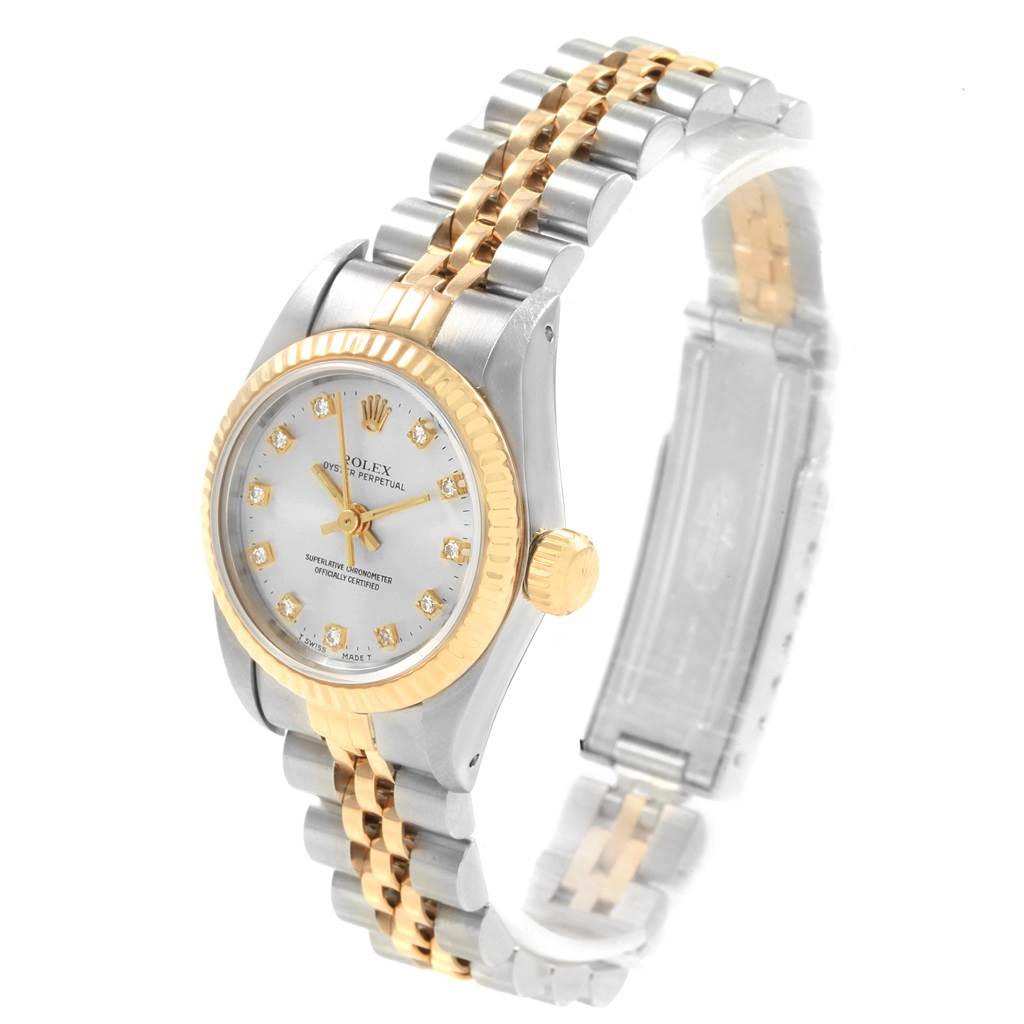 The Rolex Oyster Perpetual 67193 Women
s Steel and Gold (two tone) Silver Dial 67193 Women
s Steel and Gold (two tone) Silver Dial watch is shown at an angle displaying its gold bezel, crown, bracelet, and dial with diamond hour markers.