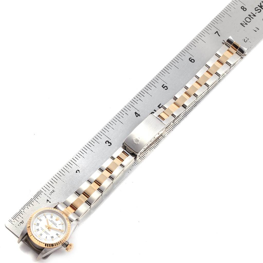 The image shows a Rolex Oyster Perpetual 67193 Women's Steel and Gold (two tone) White Dial 67193 Women's Steel and Gold (two tone) White Dial watch laid flat next to a ruler, highlighting its bracelet and clasp.