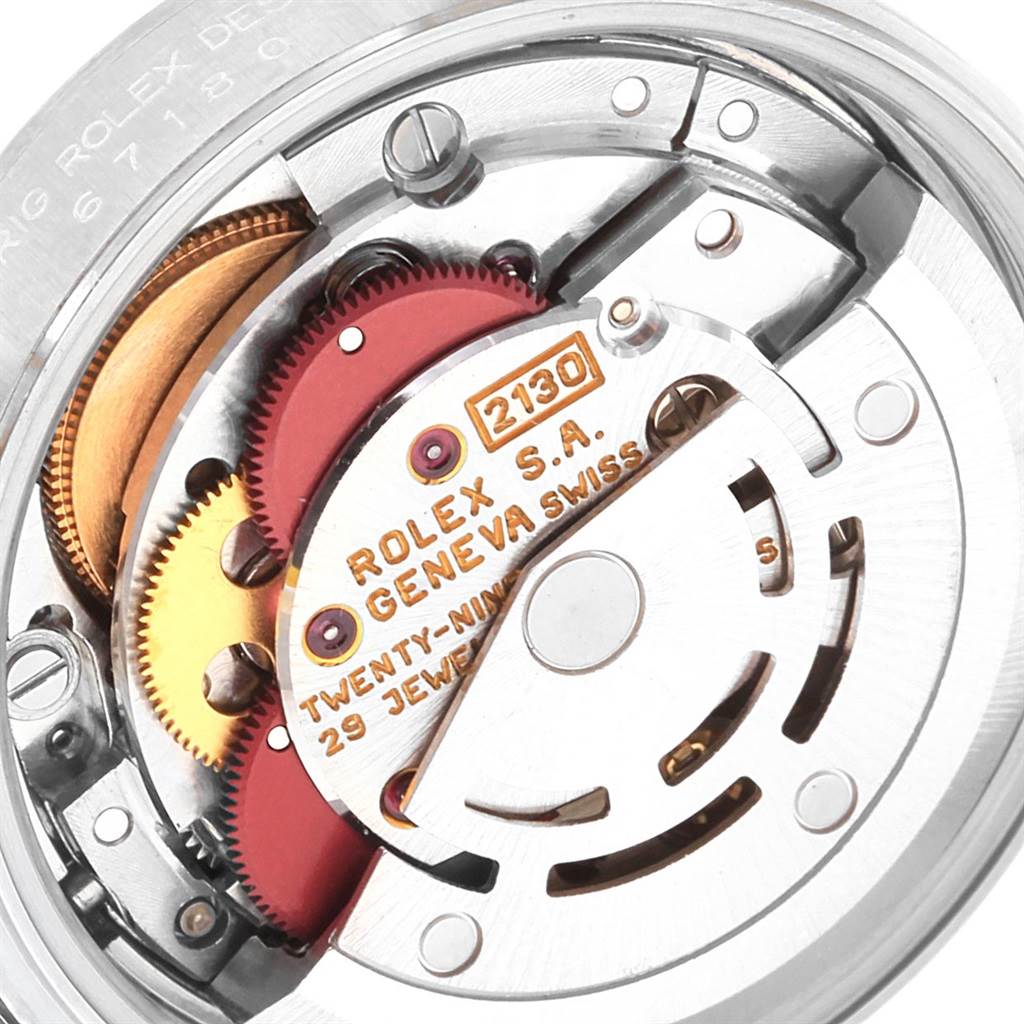 The image shows a close-up of the Rolex Oyster Perpetual 67180 Women's Stainless Steel White Dial 67180 Women's Stainless Steel White Dial movement mechanism, highlighting its internal gears and engraving.