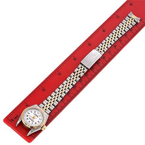 The Rolex Oyster Perpetual 67193 Women's Yellow Gold White Dial 67193 Women's Yellow Gold White Dial watch is shown at a slight diagonal angle on a red ruler, displaying the face, bezel, and bracelet.