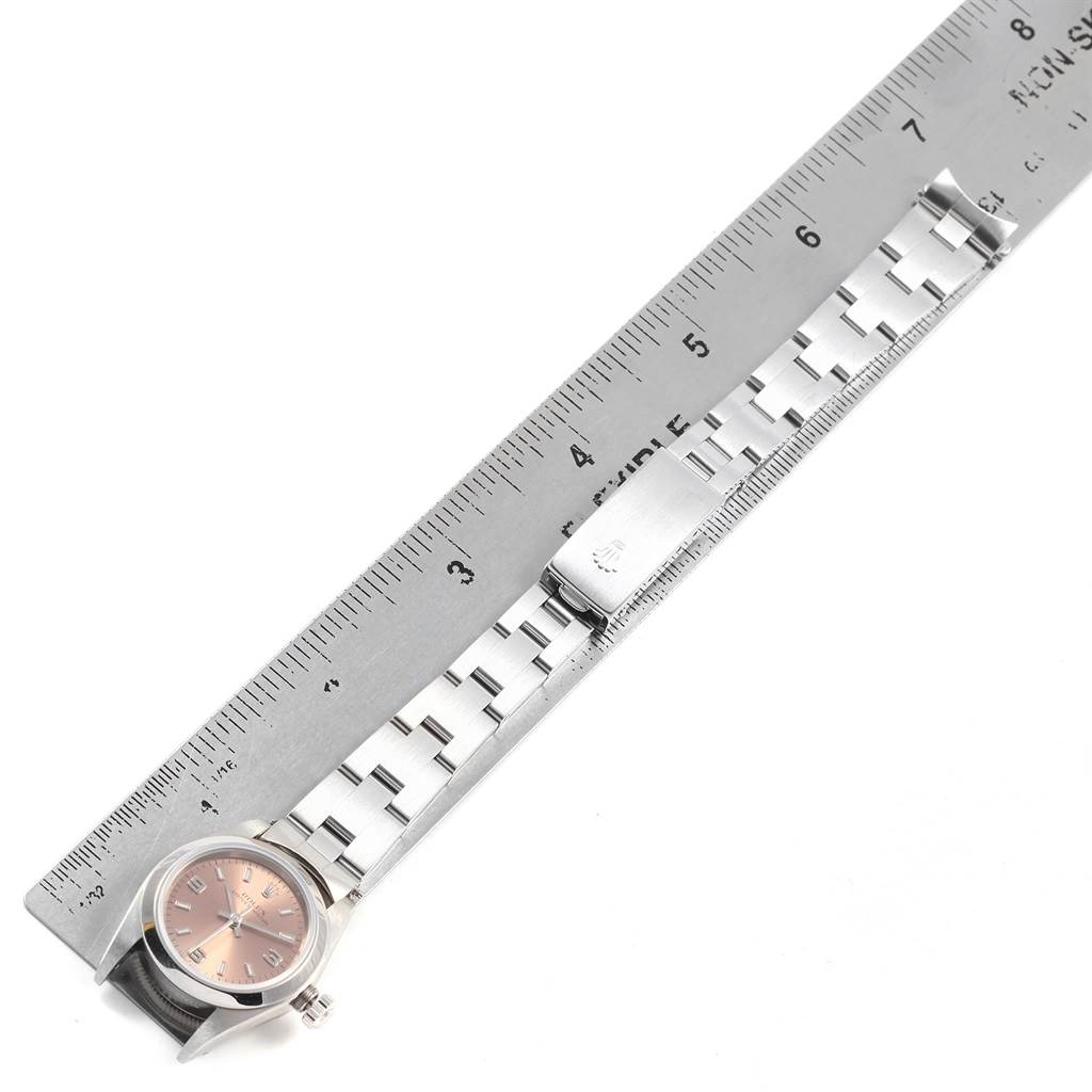 This image shows a Rolex Oyster Perpetual 76080 Women
s Stainless Steel Pink Dial 76080 Women
s Stainless Steel Pink Dial watch face, bracelet, and clasp placed alongside a ruler for size reference.