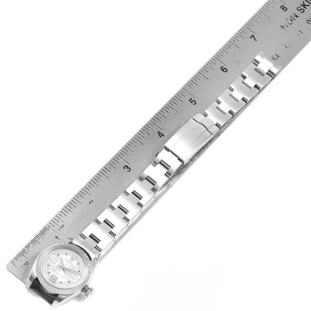 The image shows a top view of an Oyster Perpetual Rolex watch, highlighting its band alongside a ruler for scale.