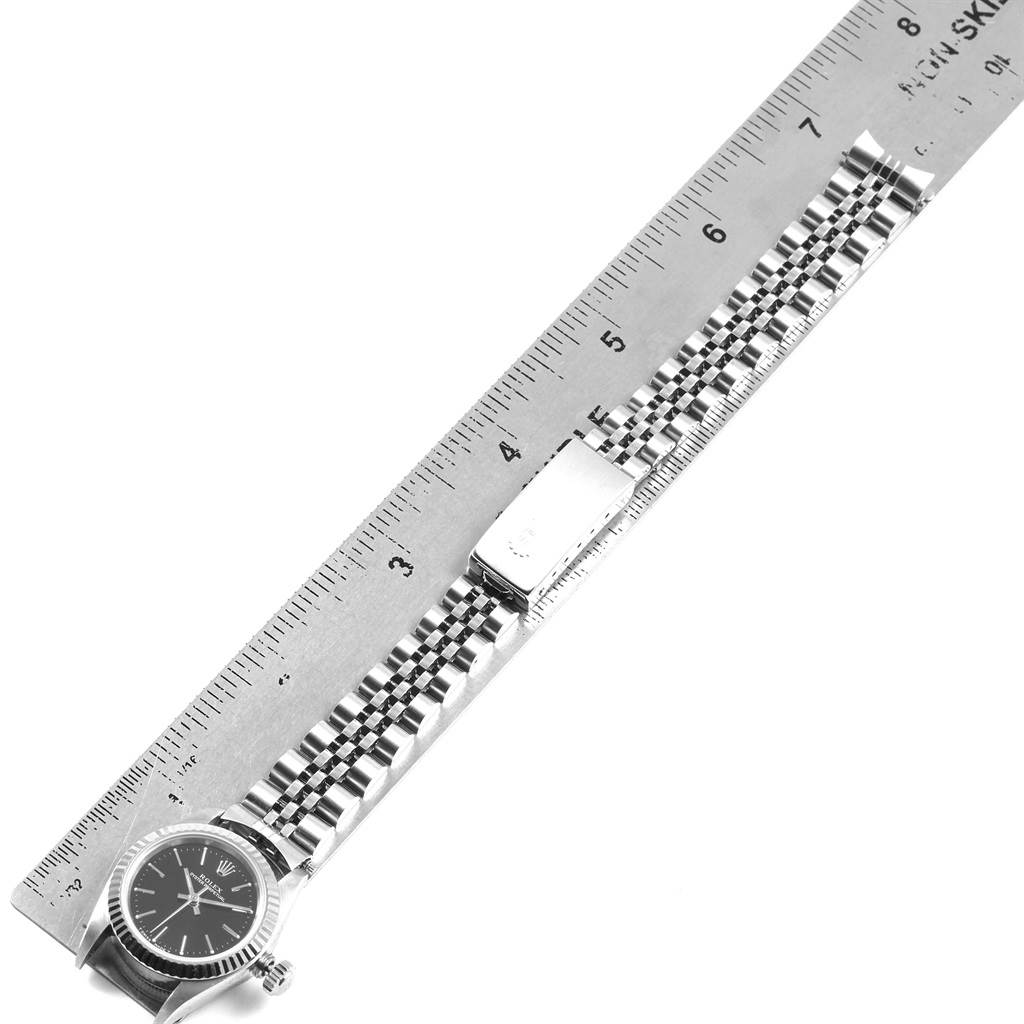 The image shows an overhead view of a Rolex Oyster Perpetual 67194 Women
s Stainless Steel Black Dial 67194 Women
s Stainless Steel Black Dial watch with a ruler measuring its bracelet and clasp.