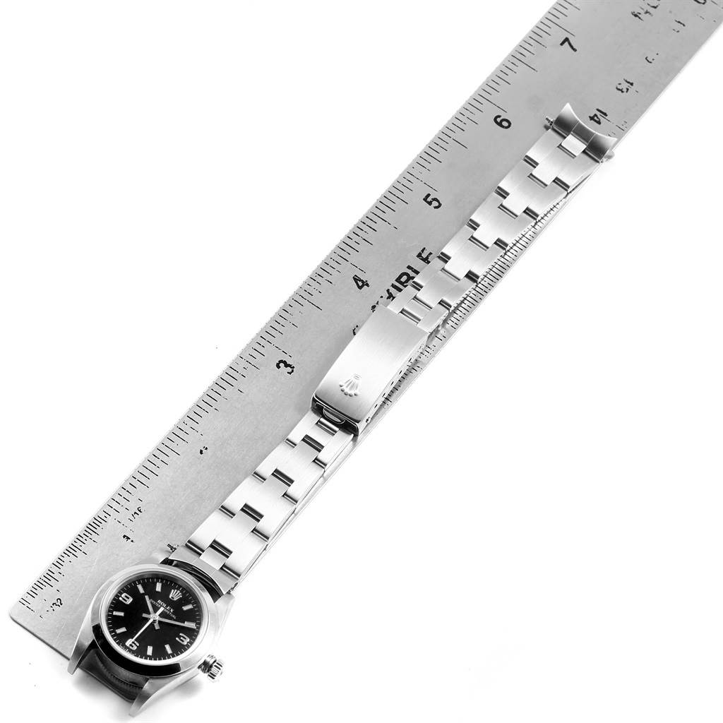 The image shows a Rolex Oyster Perpetual 76080 Women
s Stainless Steel Black Dial 76080 Women
s Stainless Steel Black Dial watch with its band and clasp laid flat next to a ruler for measurement.
