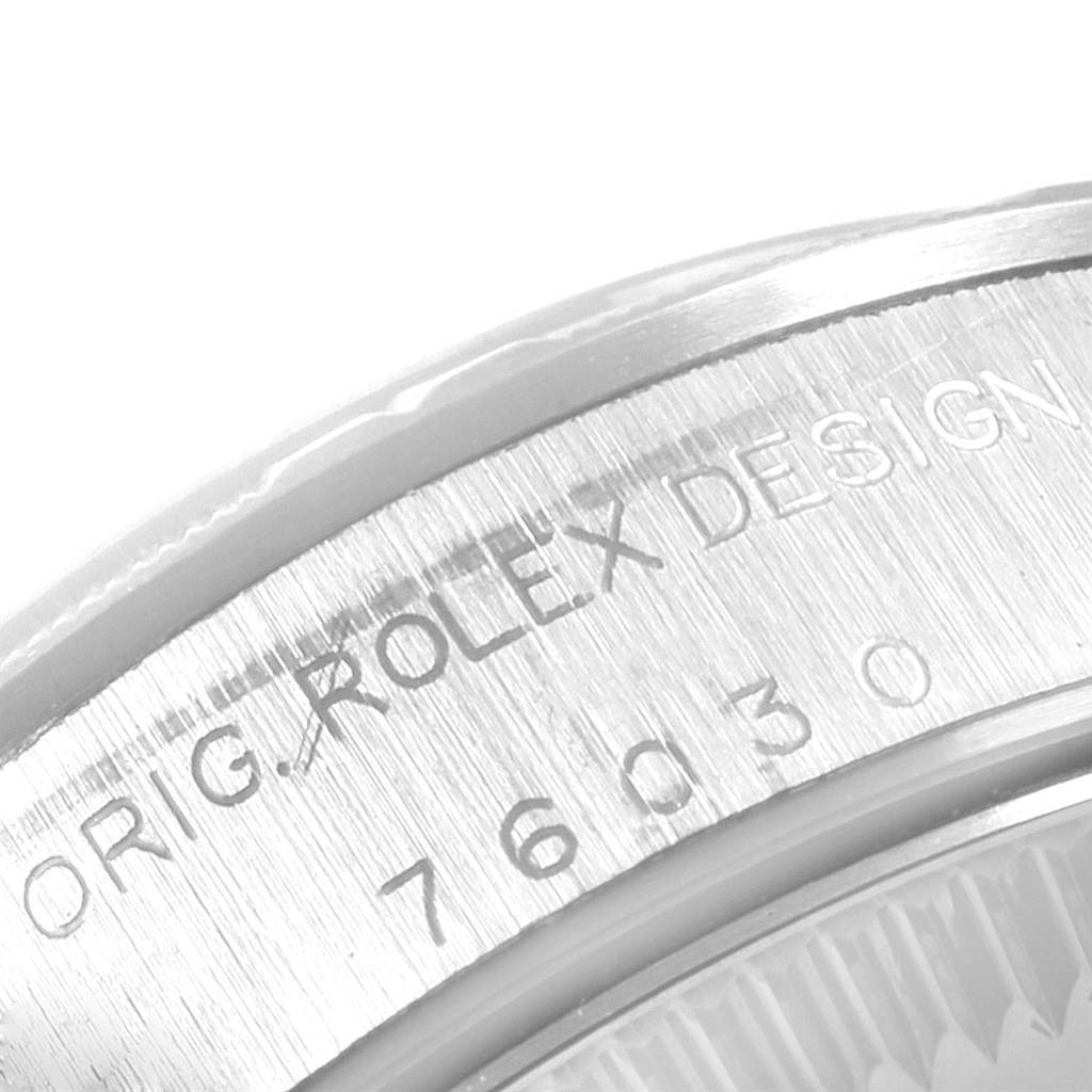 The image shows a close-up angle of the Rolex Oyster Perpetual 76030 Women
s Stainless Steel Black Dial 76030 Women
s Stainless Steel Black Dial watch
s case, highlighting the engraved serial and model numbers.