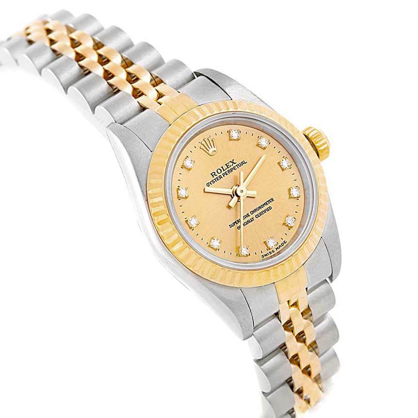This Rolex Oyster Perpetual 76193 Women
s Steel and Gold (two tone) Champagne Dial 76193 Women
s Steel and Gold (two tone) Champagne Dial watch is shown at an oblique angle, featuring its two-tone bracelet, gold bezel, and diamond-accented dial.