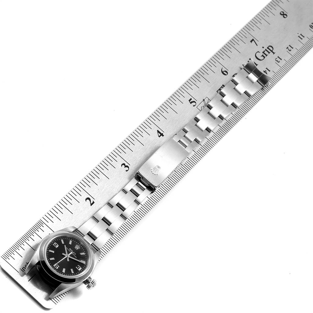 The image shows the Rolex Oyster Perpetual 76080 Women
s Stainless Steel Black Dial 76080 Women
s Stainless Steel Black Dial watch and bracelet laid flat beside a ruler for measurement.
