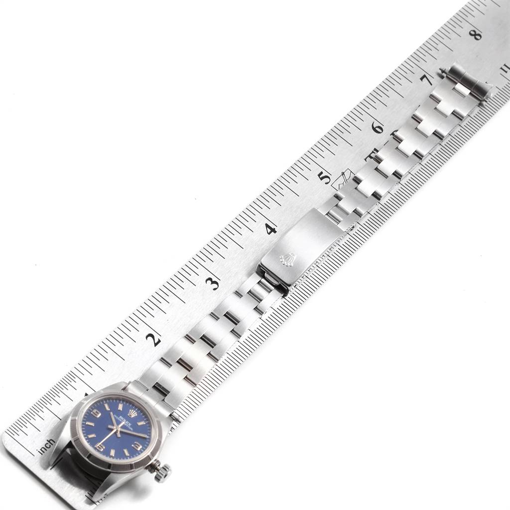 The image shows a Rolex Oyster Perpetual 67230 Women
s Stainless Steel Blue Dial 67230 Women
s Stainless Steel Blue Dial watch and bracelet laid out beside a ruler, revealing the clasp and links in detail.