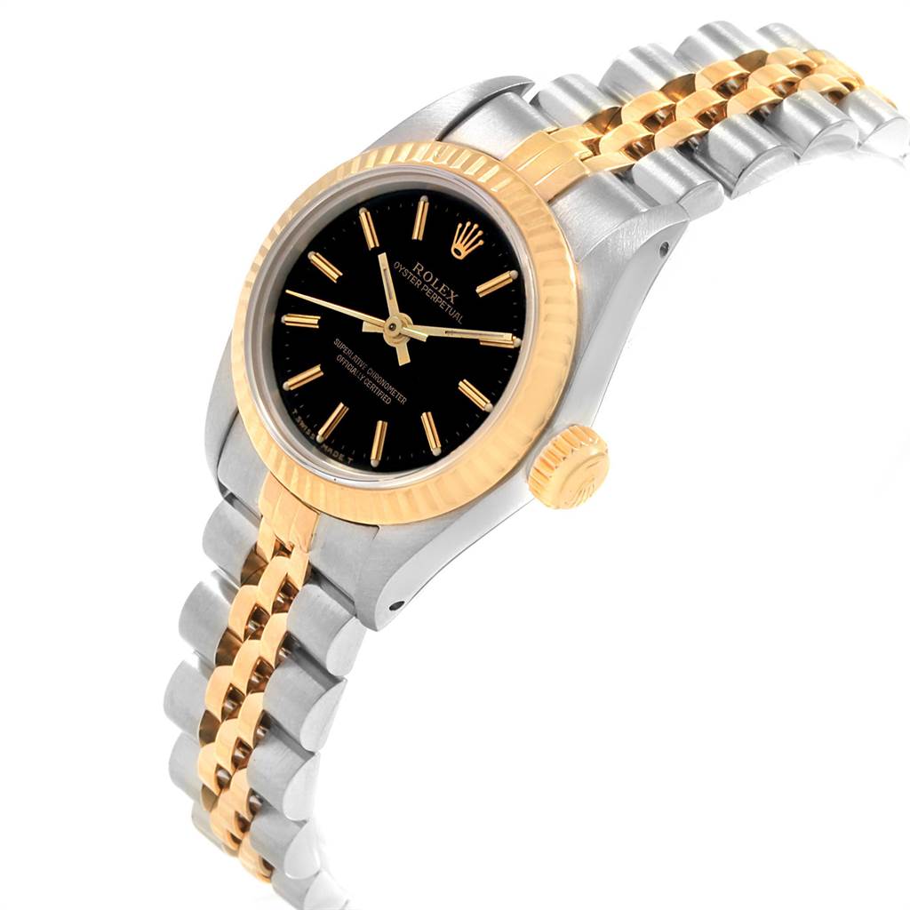 The image shows a close-up, side angle view of a Rolex Oyster Perpetual 67193 Women
s Steel and Gold (two tone) Black Dial 67193 Women
s Steel and Gold (two tone) Black Dial watch featuring a black dial, fluted bezel, crown, and two-tone bracelet.