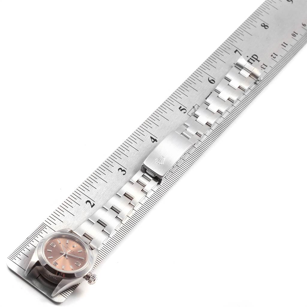 The image shows a Rolex Oyster Perpetual 76080 Women
s Stainless Steel Pink Dial 76080 Women
s Stainless Steel Pink Dial watch laid flat with the metal bracelet and clasp placed against a ruler for measurement.