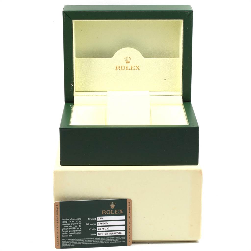 The image shows an open green and cream Rolex box and an Oyster Perpetual model information card in front of it.
