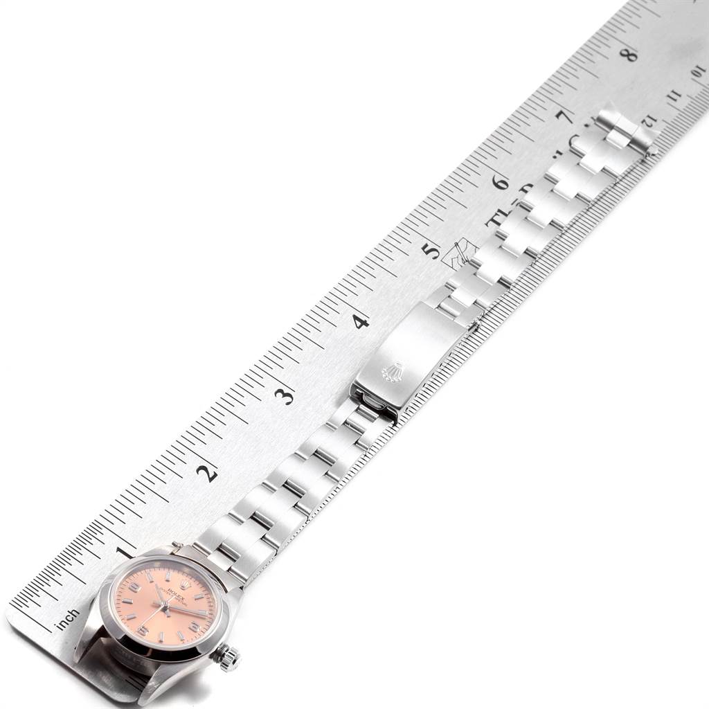The image shows a Rolex Oyster Perpetual 76080 Women
s Stainless Steel Pink Dial 76080 Women
s Stainless Steel Pink Dial watch laid flat next to a ruler, highlighting its bracelet and clasp.