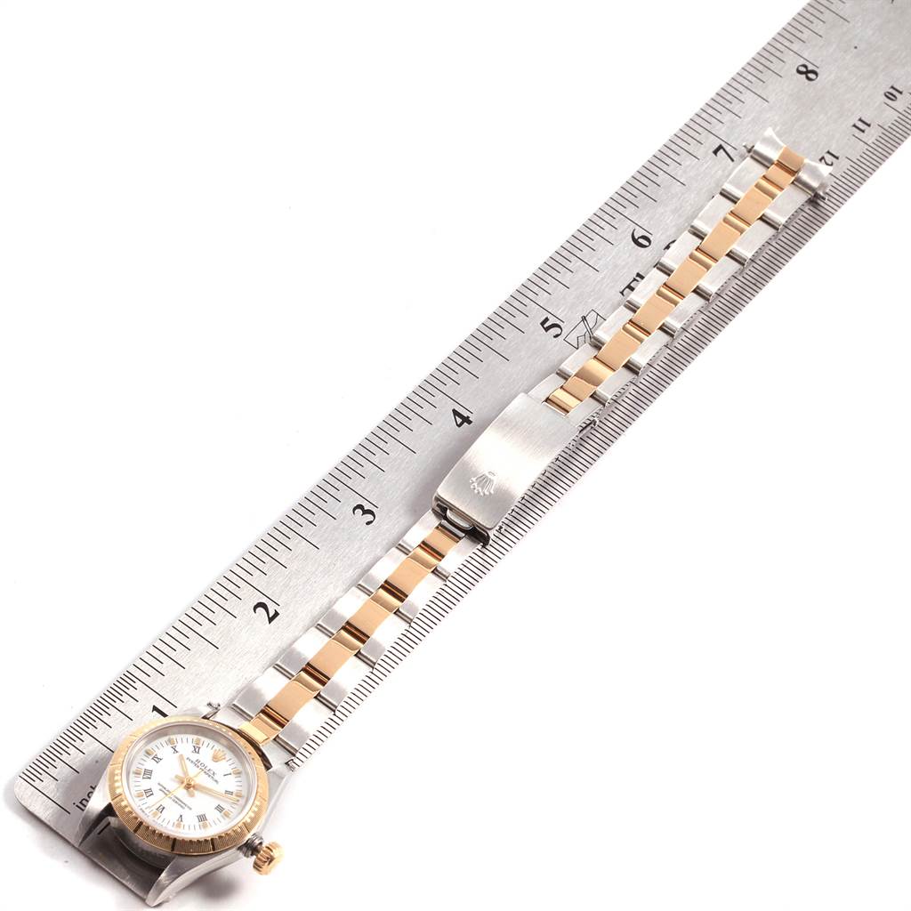 This image shows the Rolex Oyster Perpetual 67243 Women
s Steel and Gold (two tone) White Dial 67243 Women
s Steel and Gold (two tone) White Dial watch and its bracelet alongside a ruler for measurement.