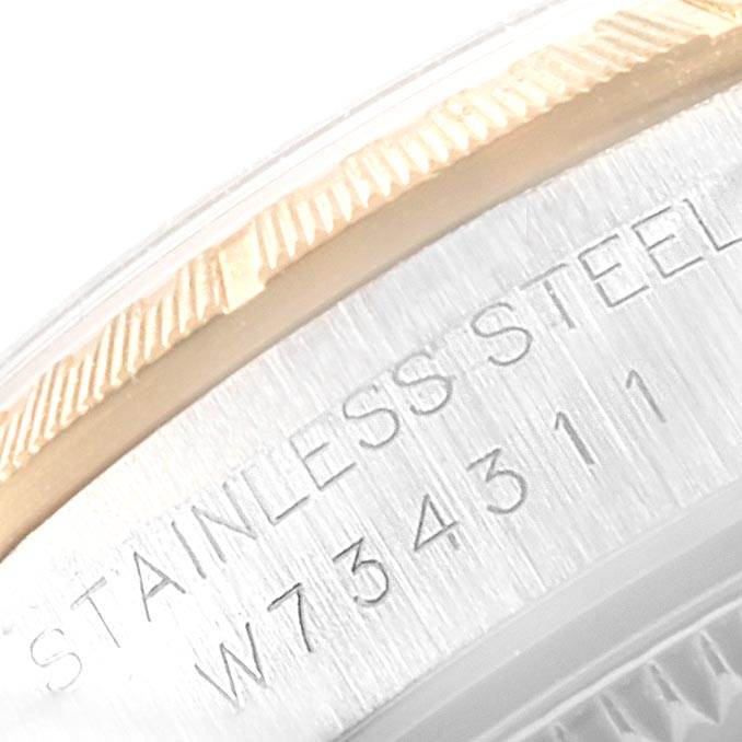 This close-up image of a Rolex Oyster Perpetual 67243 Women
s Steel and Gold (two tone) White Dial 67243 Women
s Steel and Gold (two tone) White Dial model shows part of the bezel and case back with engraved text.