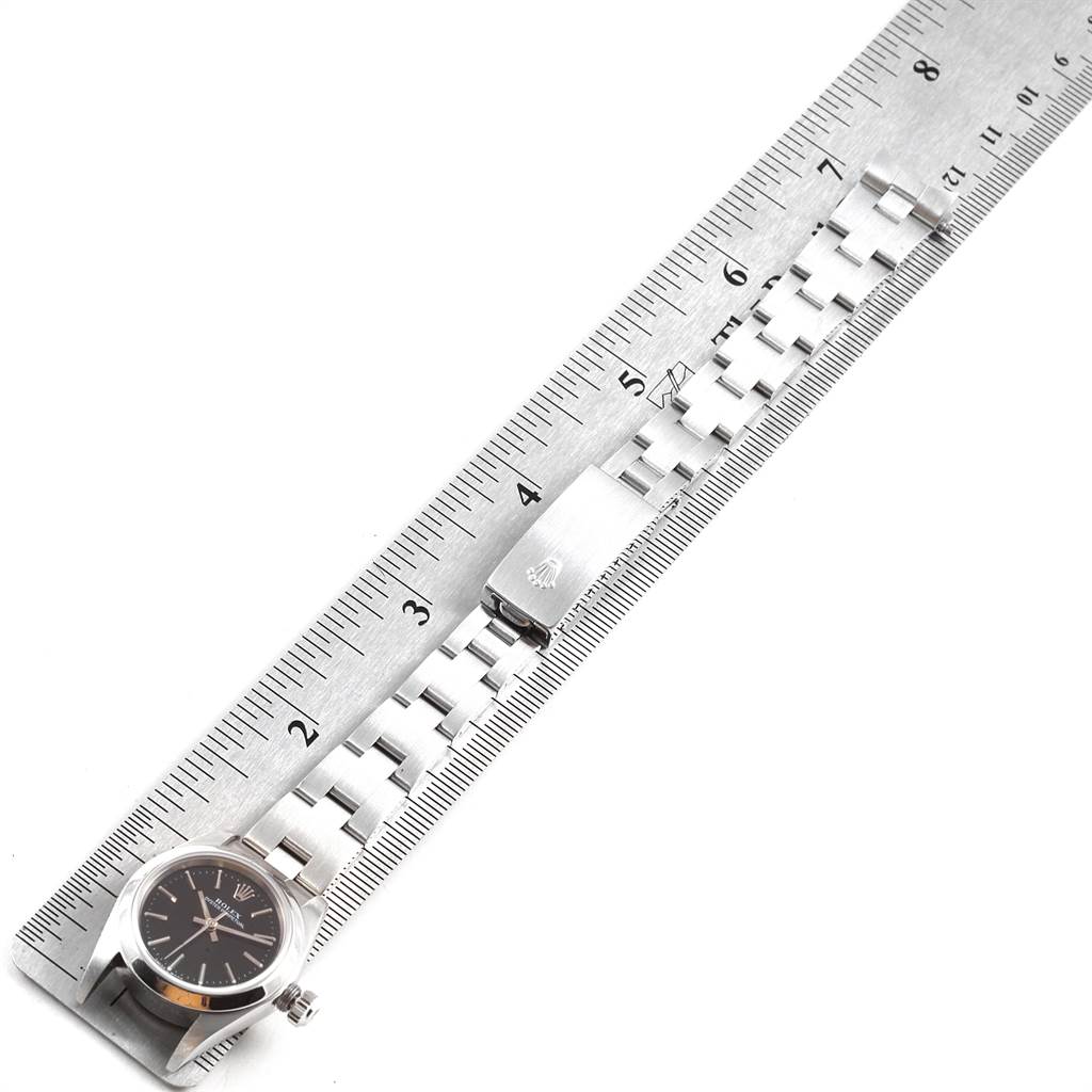 The image shows a Rolex Oyster Perpetual 76080 Women
s Stainless Steel Black Dial 76080 Women
s Stainless Steel Black Dial watch laying flat, measured alongside a ruler, displaying its face and bracelet.