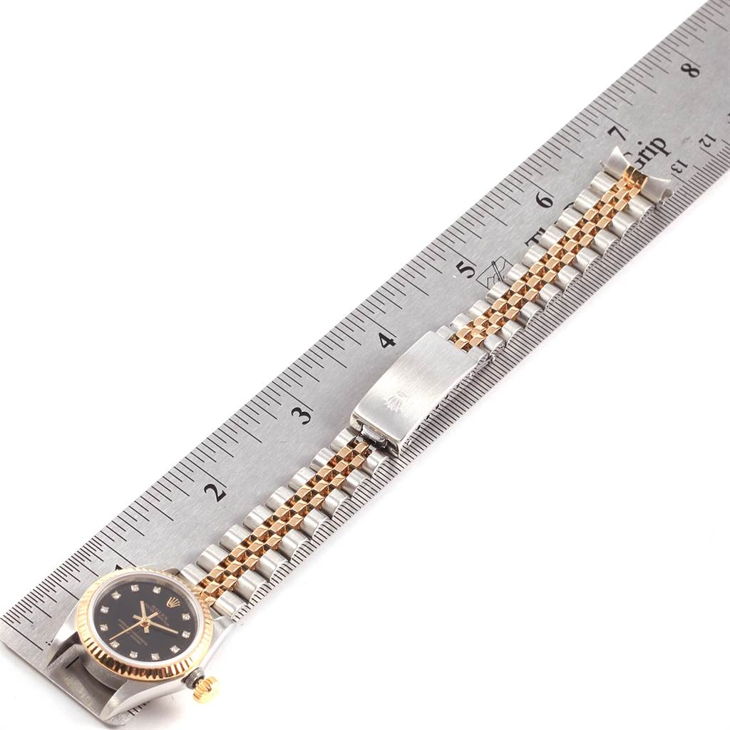 This image shows the bracelet and clasp of a Rolex Oyster Perpetual 67193 Women
s Steel and Gold (two tone) Black Dial 67193 Women
s Steel and Gold (two tone) Black Dial watch, placed alongside a ruler for measurement.