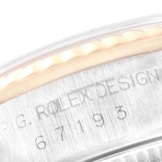 This close-up image shows the side edge of a Rolex Oyster Perpetual 67193 Women
s Steel and Gold (two tone) Black Dial 67193 Women
s Steel and Gold (two tone) Black Dial watch, highlighting the model number and "ROLEX DESIGN" engraving.