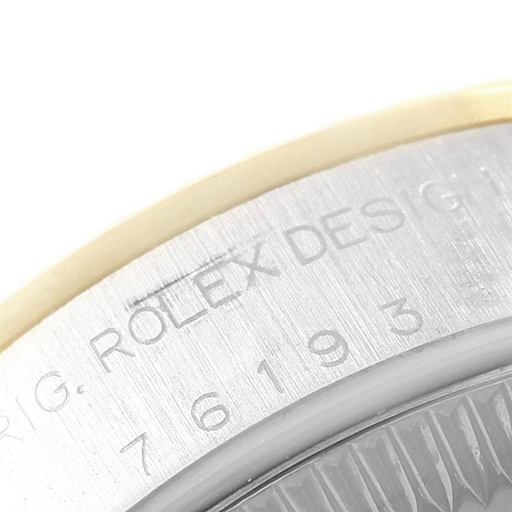 The image shows a close-up of the side of a Rolex Oyster Perpetual 76193 Women
s Steel and Gold (two tone) Black Dial 76193 Women
s Steel and Gold (two tone) Black Dial watch, featuring part of the engraved serial number and "ROLEX DESIGN" text.