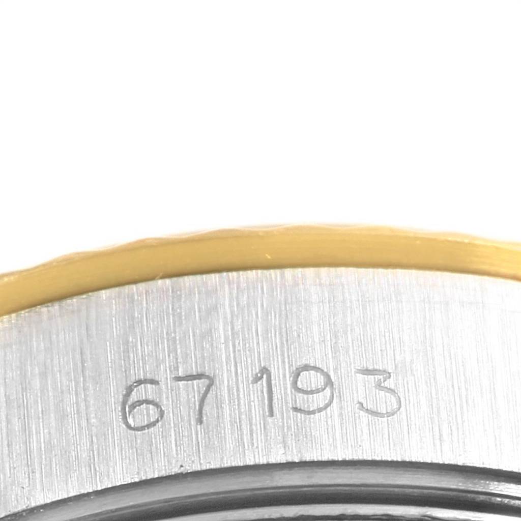 This image shows a close-up of the side of a Rolex Oyster Perpetual 67193 Women's Steel and Gold (two tone) Champagne Dial 67193 Women's Steel and Gold (two tone) Champagne Dial watch case, featuring engraved numbers and a partial gold bezel.
