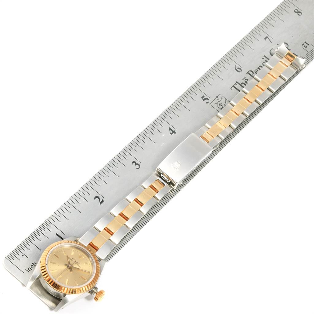 The image shows a Rolex Oyster Perpetual 67193 Women's Steel and Gold (two tone) Champagne Dial 67193 Women's Steel and Gold (two tone) Champagne Dial watch laid flat alongside a ruler, highlighting the watch's dial, bezel, and bracelet.