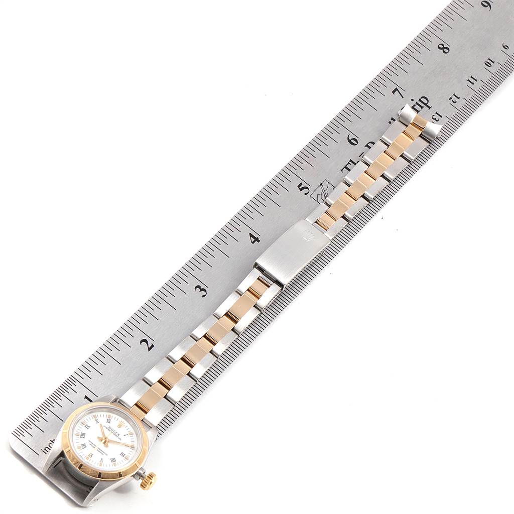 The image shows a Rolex Oyster Perpetual 67233 Women's Steel and Gold (two tone) White Dial 67233 Women's Steel and Gold (two tone) White Dial watch placed along a ruler, highlighting the band and clasp.