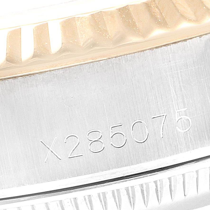 This close-up image of a Rolex Oyster Perpetual 69173 Women's Stainless Steel Black Dial 69173 Women's Stainless Steel Black Dial watch shows the engraved serial number on the case side and a portion of the fluted bezel.
