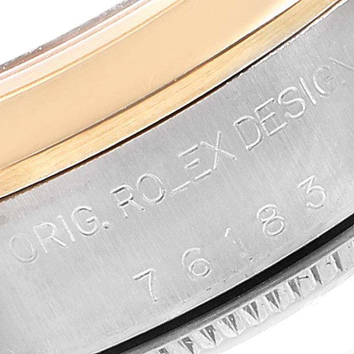 The image shows a close-up of the side of a Rolex Oyster Perpetual 76183 Women
s Steel and Gold (two tone) Champagne Dial 76183 Women
s Steel and Gold (two tone) Champagne Dial watch, highlighting the bezel and serial engravings.