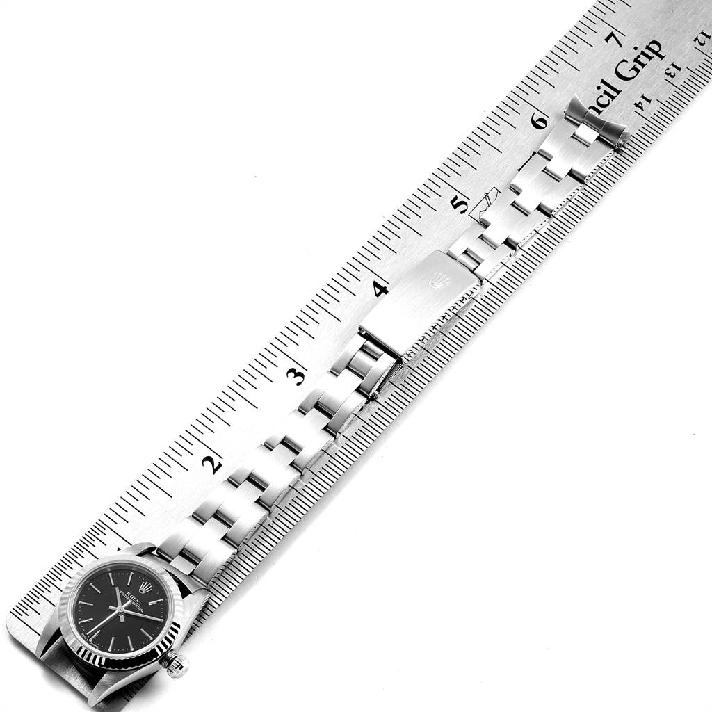 The image shows a Rolex Oyster Perpetual 76094 Women's Stainless Steel Black Dial 76094 Women's Stainless Steel Black Dial model watch with the face, bracelet, and clasp, placed against a ruler from an overhead angle.