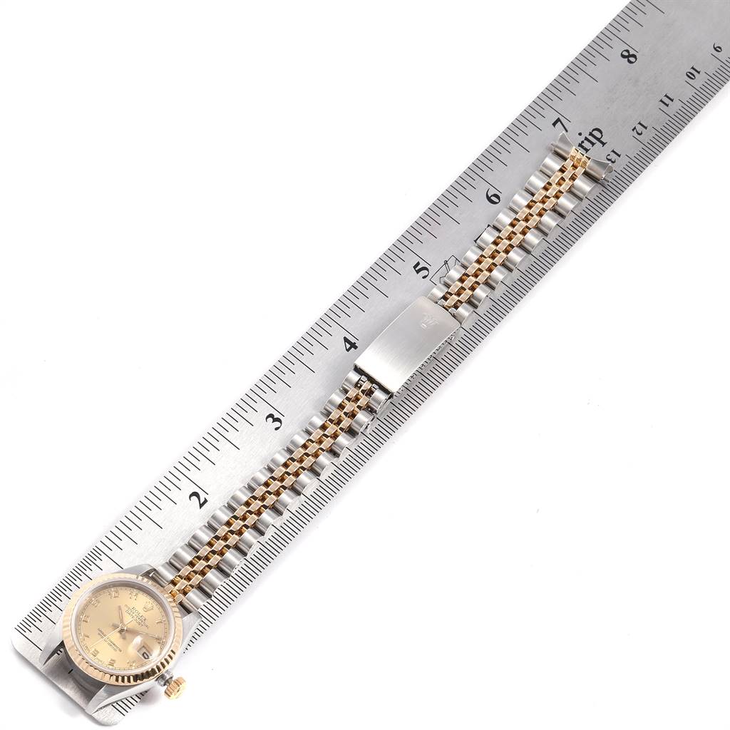 This image shows a Rolex Oyster Perpetual 69173 Women's Stainless Steel Champagne Dial 69173 Women's Stainless Steel Champagne Dial watch laid flat against a ruler, highlighting the watch face, bracelet, and clasp.