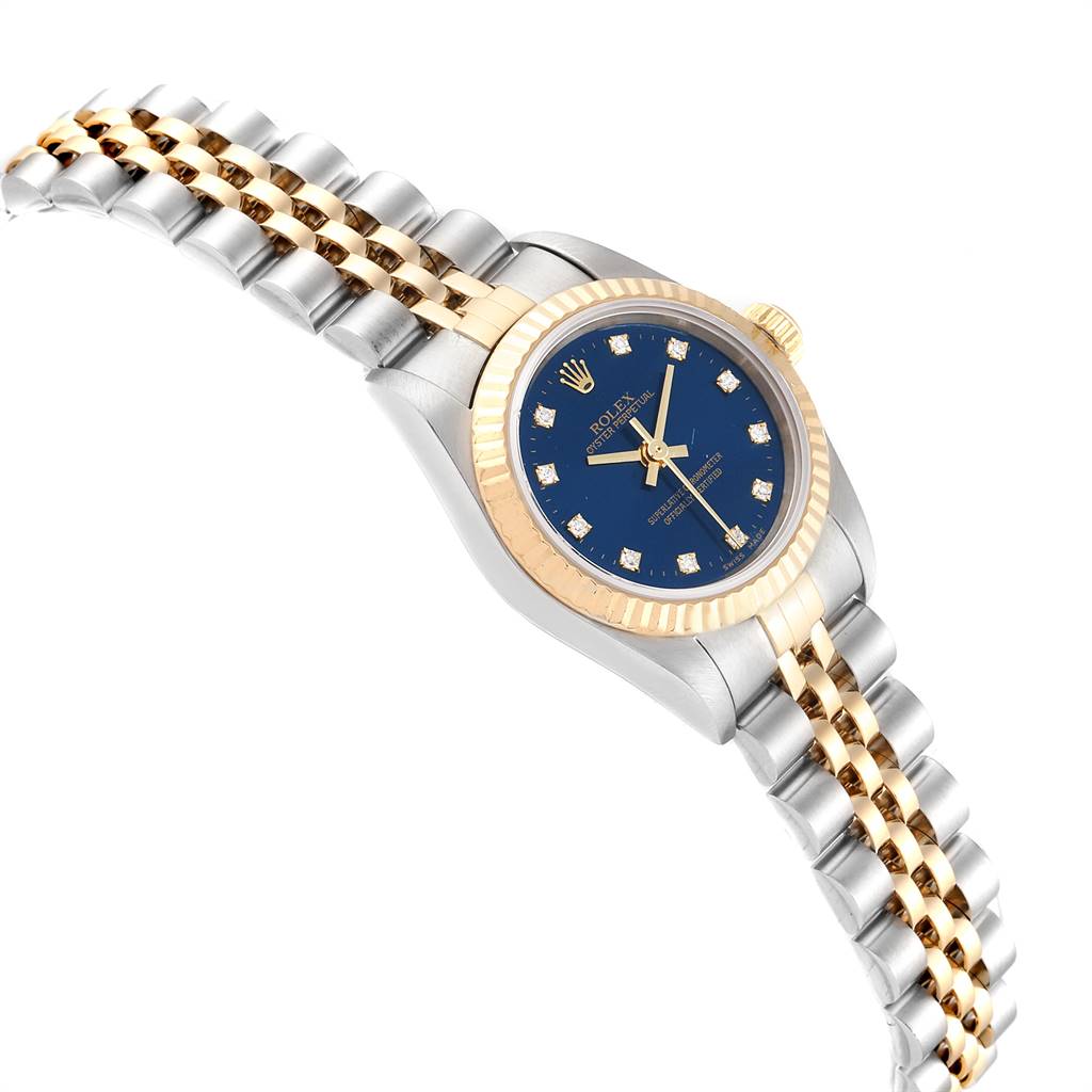 The image shows a side angle of a Rolex Oyster Perpetual 76193 Women
s Steel and Gold (two tone) Blue Dial 76193 Women
s Steel and Gold (two tone) Blue Dial watch featuring a gold bezel, blue dial, and two-tone bracelet.