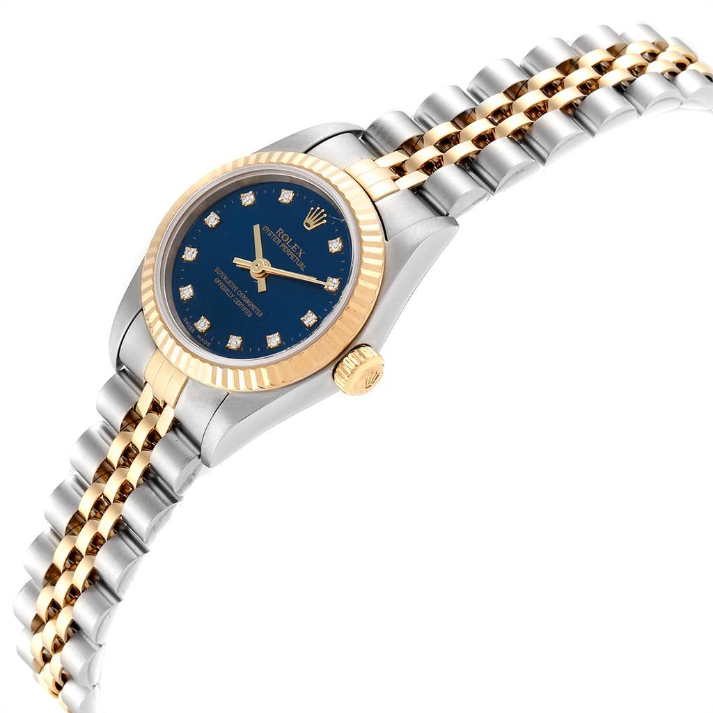 The image shows the Rolex Oyster Perpetual 76193 Women
s Steel and Gold (two tone) Blue Dial 76193 Women
s Steel and Gold (two tone) Blue Dial watch at an angle highlighting its blue dial, gold bezel, and two-tone bracelet.