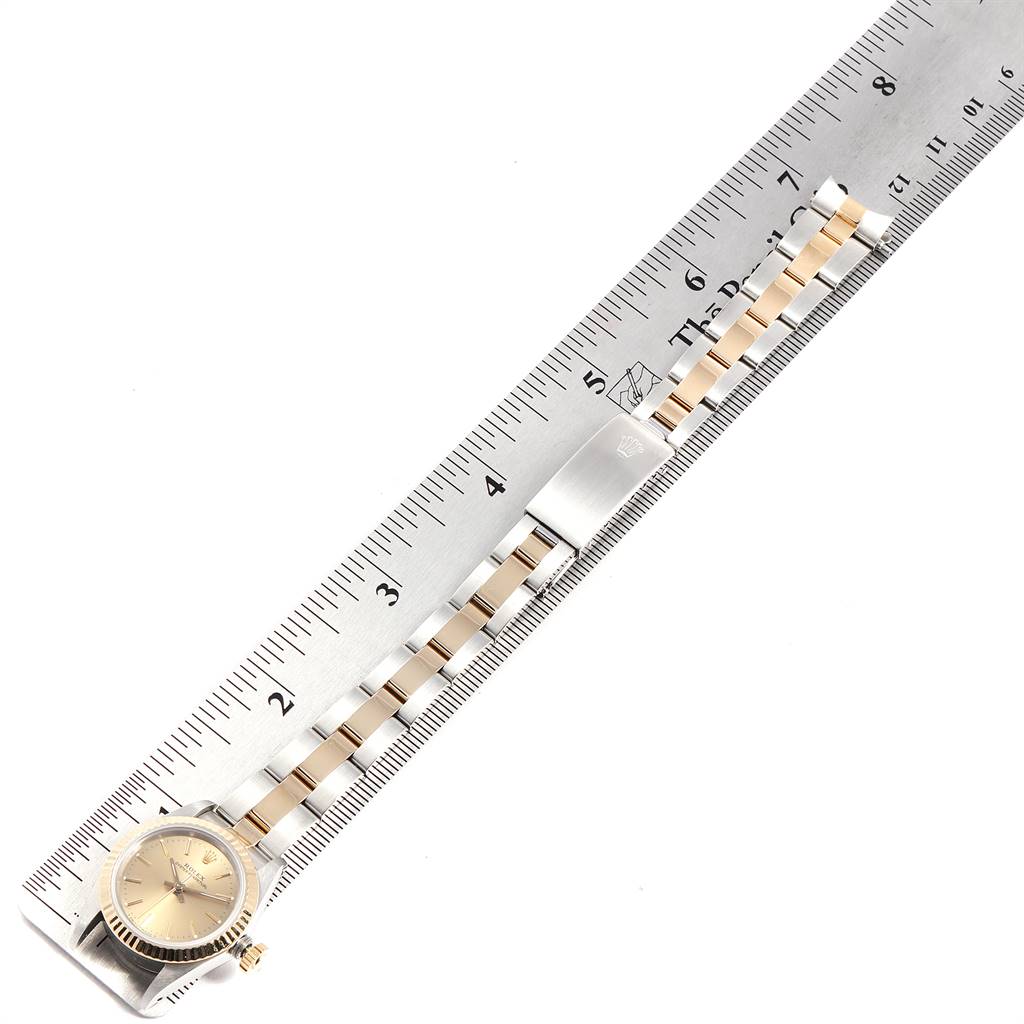 The image shows a side view of a Rolex Oyster Perpetual 67193 Women's Steel and Gold (two tone) Champagne Dial 67193 Women's Steel and Gold (two tone) Champagne Dial watch and its band alongside a measuring ruler.