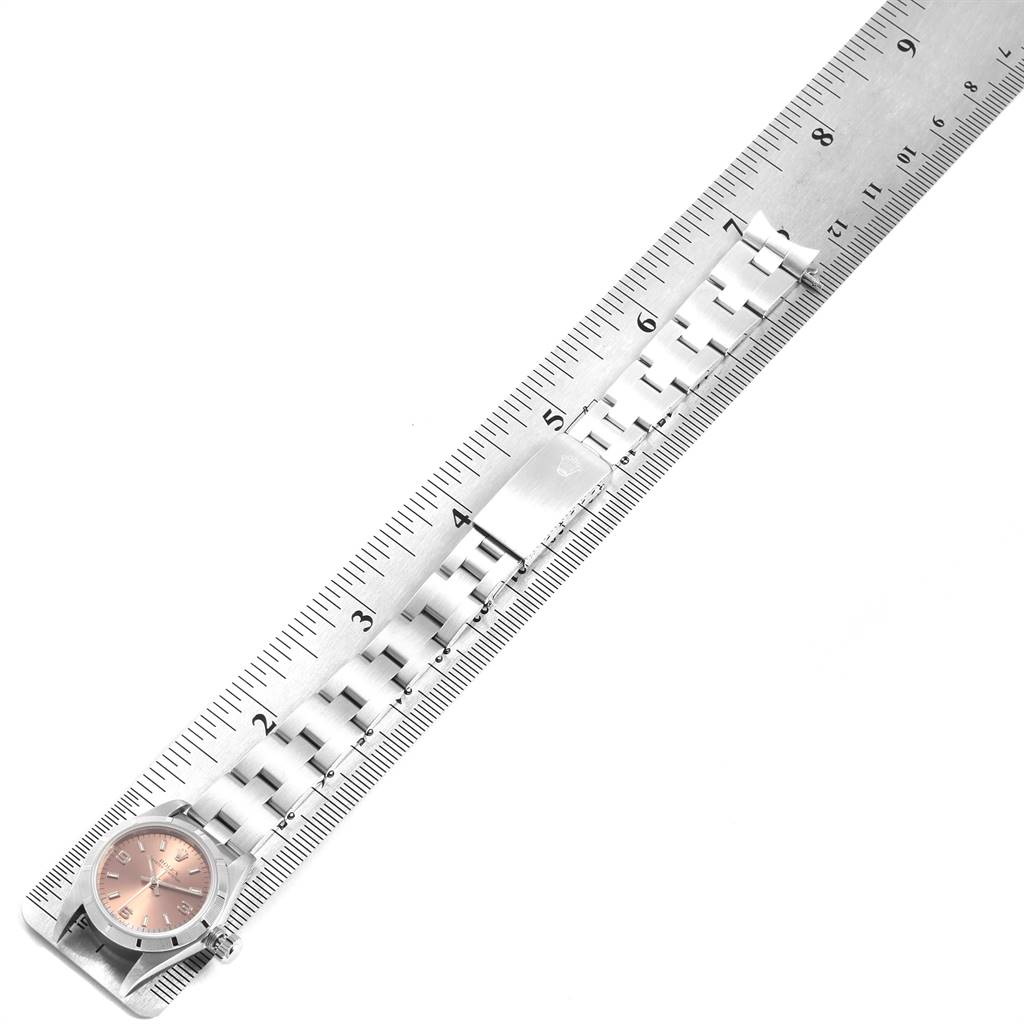 The image shows a Rolex Oyster Perpetual 67230 Women's Stainless Steel Pink Dial 67230 Women's Stainless Steel Pink Dial watch and its metal bracelet measured with a ruler from an overhead angle.