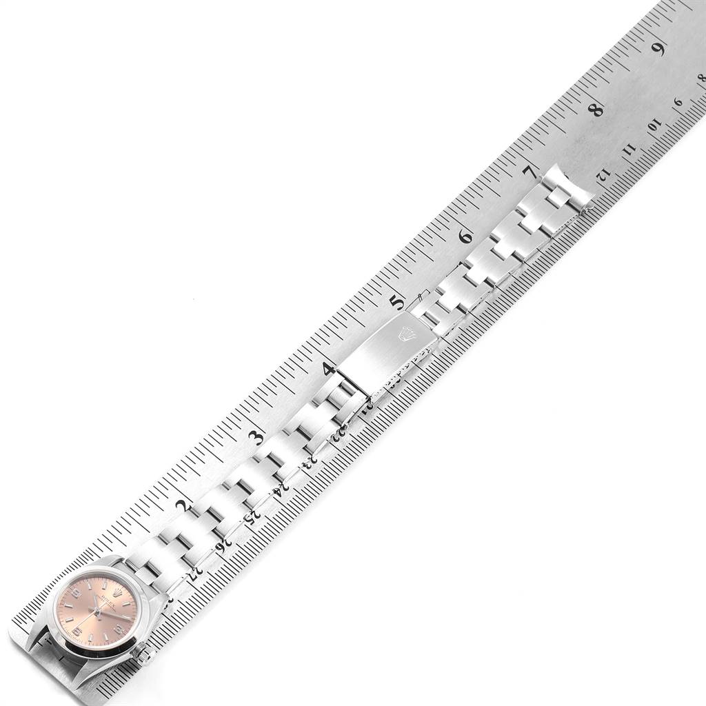 The image shows a Rolex Oyster Perpetual 76080 Women's Stainless Steel Pink Dial 76080 Women's Stainless Steel Pink Dial watch laid flat with its bracelet aligned next to a ruler for measurement.