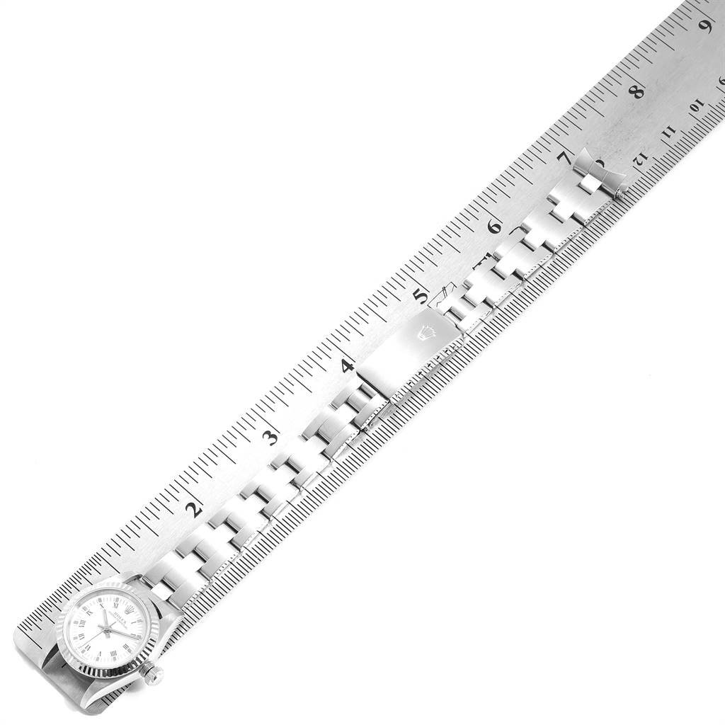 The image shows a Rolex Oyster Perpetual 76094 Women
s Stainless Steel White Dial 76094 Women
s Stainless Steel White Dial watch and its bracelet placed against a ruler for measurement.