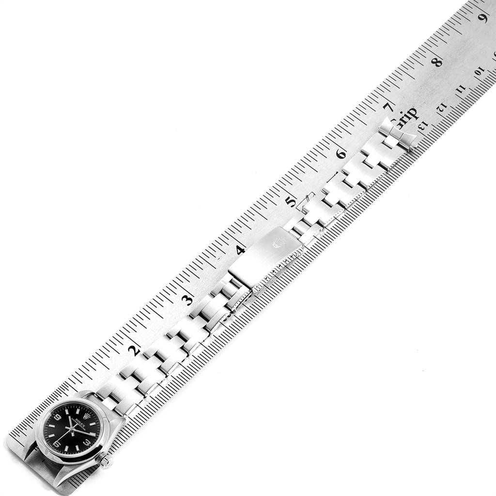 This image shows the Rolex Oyster Perpetual 76080 Women's Stainless Steel Black Dial 76080 Women's Stainless Steel Black Dial watch face and bracelet placed along a ruler for measurement.