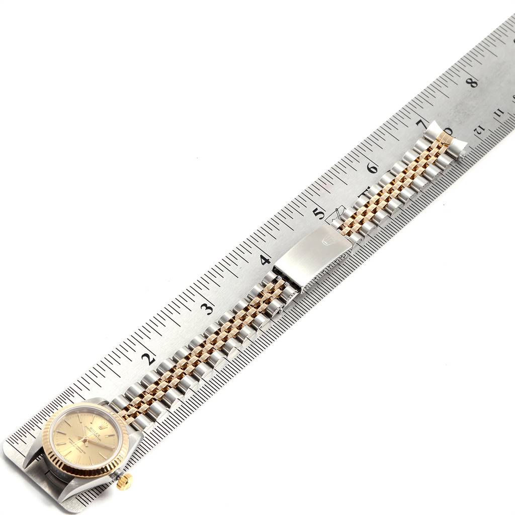 The Rolex Oyster Perpetual 67193 Women
s Steel and Gold (two tone) Champagne Dial 67193 Women
s Steel and Gold (two tone) Champagne Dial watch is shown laid flat with a ruler for size reference, displaying its face and bracelet.