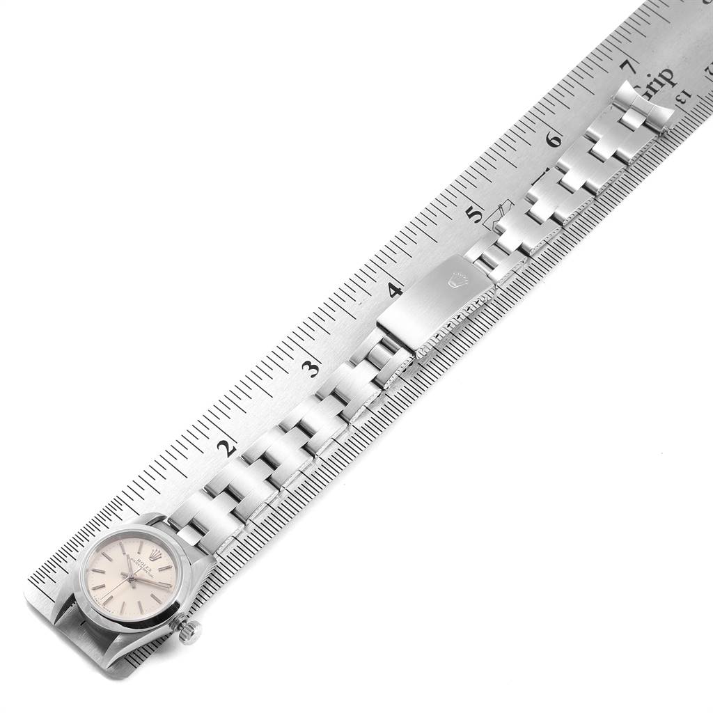 The image shows a Rolex Oyster Perpetual 67180 Women's Stainless Steel Silver Dial 67180 Women's Stainless Steel Silver Dial watch laid flat on a ruler, highlighting the dial, bracelet, and clasp.