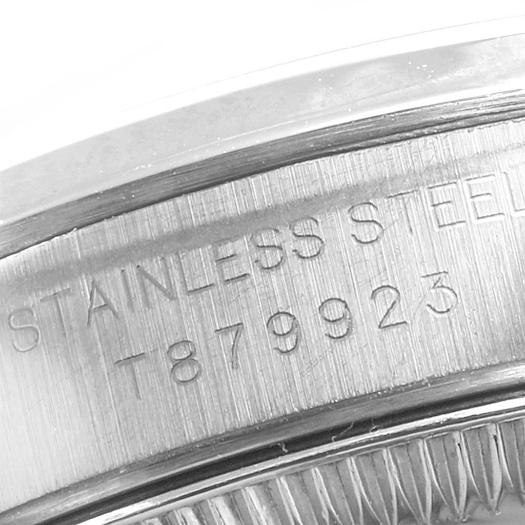 The image shows a close-up of the casing edge of a Rolex Oyster Perpetual 67180 Women's Stainless Steel Silver Dial 67180 Women's Stainless Steel Silver Dial watch, highlighting the "STAINLESS STEEL" engraving and serial number.