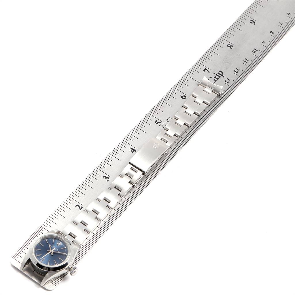 The Rolex Oyster Perpetual 67180 Women
s Stainless Steel Blue Dial 67180 Women
s Stainless Steel Blue Dial watch is shown from the top angle, displaying its blue dial and metal bracelet aligned along a ruler.