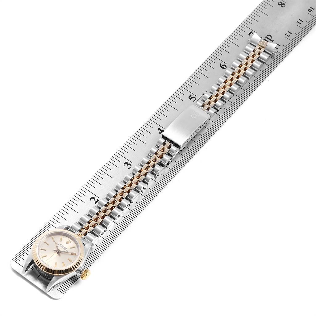 The Rolex Oyster Perpetual 67193 Women's Steel and Gold (two tone) Silver Dial 67193 Women's Steel and Gold (two tone) Silver Dial watch is shown from a top-down angle, displaying the dial, bracelet, and clasp set against a ruler.