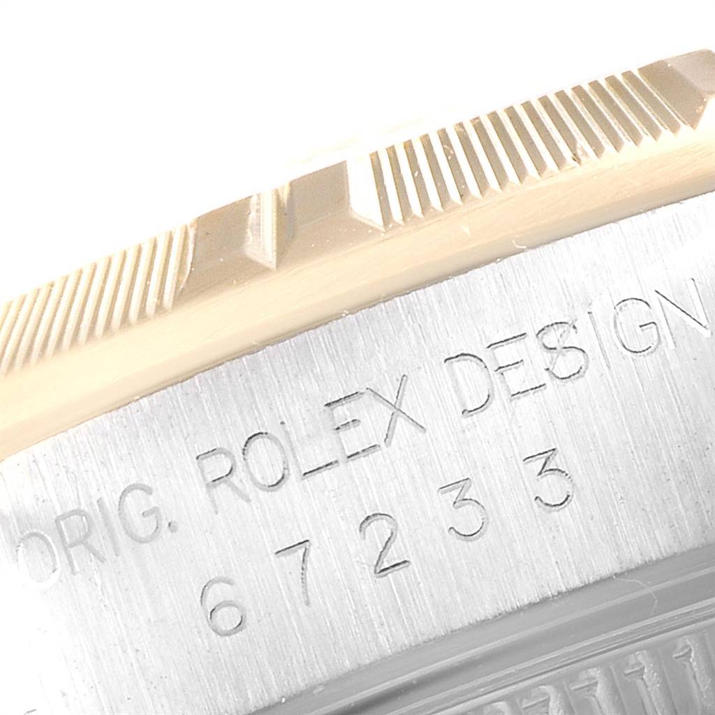 This close-up image shows the serial number and fluted bezel of a Rolex Oyster Perpetual 67233 Women's Steel and Gold (two tone) Grey Dial 67233 Women's Steel and Gold (two tone) Grey Dial watch.